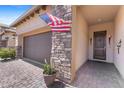 Close-up of the front entrance of the house with beautiful stone accents, an American flag, and a brick driveway at 6948 E Quill St, Mesa, AZ 85207