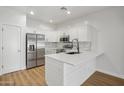 Bright white kitchen with stainless steel appliances, quartz countertops, island, and wood-look flooring at 7601 E Roosevelt St # 1012, Scottsdale, AZ 85257