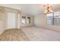 Spacious living room with wood floors in entry, large windows, and stylish chandelier at 15105 W Glenrosa Ave, Goodyear, AZ 85395
