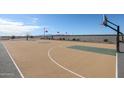 Community basketball court surrounded by perimeter wall, decorative landscaping, and mountain views at 17373 W Jessie Ln, Surprise, AZ 85387