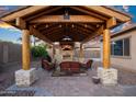 Inviting outdoor living space featuring a covered patio, stone fireplace, and comfortable seating area at 18544 W Devonshire Ave, Goodyear, AZ 85395