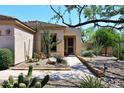 View of tan home with landscaped desert foliage leading to secure front door at 6966 E Bramble Berry Ln, Scottsdale, AZ 85266
