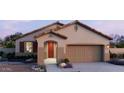 Charming single-story home showcasing a two-car garage, desert landscaping, and a covered entryway at 22631 W Irma Ln, Surprise, AZ 85387