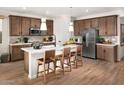 Modern kitchen featuring a stainless-steel refrigerator, wooden cabinetry, and an island with seating at 22631 W Irma Ln, Surprise, AZ 85387