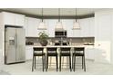 Modern kitchen boasts white cabinetry, stainless steel appliances, and an island with stylish black stools at 4808 S 232Nd Ln, Buckeye, AZ 85326