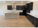 Modern kitchen featuring dark cabinets, stainless steel appliances, a large island, and wood-look tile flooring at 7259 E Blissful Breeze Ln, San Tan Valley, AZ 85143