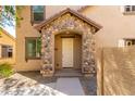 Inviting front entrance with stone pillars, neutral stucco, and a neatly maintained yard at 935 E Agua Fria Ln, Avondale, AZ 85323