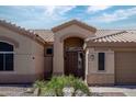 Front entrance featuring a decorative door, tile roof, and desert landscaping at 1398 W Windhaven Ave, Gilbert, AZ 85233