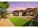 Expansive backyard with lush artificial grass, a covered patio, and desert landscaping at 15456 W Corrine Dr, Surprise, AZ 85379