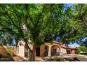 Charming home with a welcoming front porch and a second-story balcony, framed by mature trees at 15456 W Corrine Dr, Surprise, AZ 85379