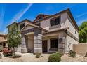 Inviting two-story home features a covered porch, desert landscaping, neutral stucco and stylish grey accents at 16386 W Sierra St, Surprise, AZ 85388