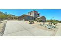 Exterior view of a home with a large driveway, three-car garage, and desert surroundings at 3903 E Melody Dr, Phoenix, AZ 85042