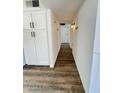 Hallway with wood-look flooring, leading to rooms with white doors, and featuring built-in storage at 4916 W Earll Dr, Phoenix, AZ 85031