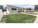 Charming white home showcasing a lush green lawn, walkway, and a gray pickup truck parked in the driveway at 5808 W Myrtle Ave, Glendale, AZ 85301