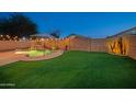 Large backyard with an artificial lawn and pool featuring a rock waterfall and lush desert landscaping at 6309 W Hughes Dr, Phoenix, AZ 85043