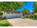 White home with a spacious driveway and well-manicured lawn and mature landscaping at 1423 E 1St St, Mesa, AZ 85203