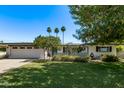 Charming single-story home with a well-manicured lawn and palm trees under a clear blue sky at 1423 E 1St St, Mesa, AZ 85203