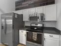 Well-equipped kitchen features stainless steel appliances, white cabinets, and gray countertops at 14728 W Redfield Rd, Surprise, AZ 85379