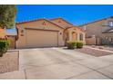 A tan single-story home featuring desert landscaping, a two-car garage and a comfortable aesthetic at 17693 W Lincoln St, Goodyear, AZ 85338