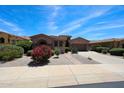 Inviting single-story home features lush desert landscaping, a brick walkway, and a two-car garage at 17975 W Willow Dr, Goodyear, AZ 85338