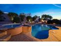 Inviting backyard with a large pool and spa, accented by lush landscaping and stone accents at 17975 W Willow Dr, Goodyear, AZ 85338