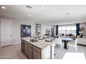 Open concept kitchen with granite countertops and a central island flowing into the dining and living areas at 18134 W Creedance Blvd, Surprise, AZ 85387