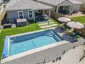 Aerial view of the backyard featuring a sparkling pool, lounge chairs, manicured artificial grass, and a hot tub at 40848 W Hillman Dr, Maricopa, AZ 85138