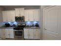Updated kitchen with white cabinets, stainless steel appliances, granite countertops and decorative backsplash at 8419 S 40Th Dr, Laveen, AZ 85339