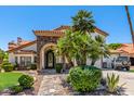 Stunning home entrance featuring an arched stone entryway, wrought iron door, and desert landscaping at 10386 N 96Th Pl, Scottsdale, AZ 85258
