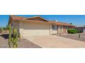 Single-story home with a spacious driveway, desert landscaping, and neutral-toned exterior on a clear day at 11627 S Iroquois Dr, Phoenix, AZ 85044