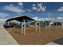 Community playground featuring swings and a covered play structure with slides and wood chip ground cover at 18090 W Creedance Blvd, Surprise, AZ 85387