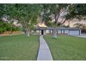 Quaint home showcasing a verdant lawn, mature trees, and a welcoming front porch with rocking chairs at 1886 S 141St Pl, Gilbert, AZ 85295