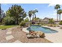 Beautiful backyard featuring a rock water feature, lush landscaping, and a refreshing pool at 19010 N 35Th Way, Phoenix, AZ 85050