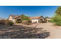 Beige single-story house featuring desert landscaping, shrubbery, and a driveway at 6032 W Grovers Ave, Glendale, AZ 85308