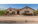 Beige single-story house featuring desert landscaping, foliage, and a walkway to the entrance at 6032 W Grovers Ave, Glendale, AZ 85308