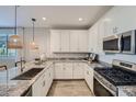 Bright kitchen showcasing white cabinets, granite countertops, stainless steel appliances, and a stylish woven pendant light at 8048 E Paloma Ave, Mesa, AZ 85212