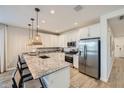 Well-lit kitchen features a granite island with seating, stainless steel appliances, white cabinets, and wood-look flooring at 8048 E Paloma Ave, Mesa, AZ 85212