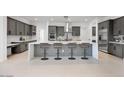 Elegant kitchen featuring a large island with seating, gray cabinetry, and stainless steel appliances at 8318 W Palo Verde Dr, Glendale, AZ 85305