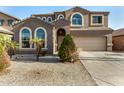 Two-story home with a two-car garage, arched windows, and low maintenance desert landscaping at 9207 W Kirby Ave, Tolleson, AZ 85353