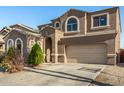 Two-story home with attached two car garage, arched windows, desert landscaping, and concrete driveway at 9207 W Kirby Ave, Tolleson, AZ 85353