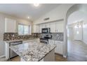 Updated kitchen features granite countertops, stainless steel appliances, mosaic backsplash, and island sink at 9330 E Plana Ave, Mesa, AZ 85212