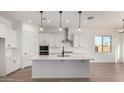 Bright kitchen featuring white cabinets, stainless steel appliances, a spacious island, and modern pendant lighting at 16455 W Avenida Del Sol --, Surprise, AZ 85387