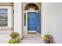 Inviting home entrance featuring a blue front door, security screen, arched window, and colorful potted flowers at 1755 N 74Th Pl, Mesa, AZ 85207