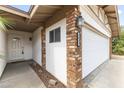 A close-up view of the brick siding, white painted stucco, front door, and a two-car garage on a sunny day at 2633 E Garnet Ave, Mesa, AZ 85204