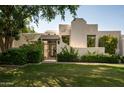 Front view of a stucco home with green lawn, gate, and mature trees at 3186 E Stella Ln, Phoenix, AZ 85016