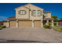 Beautiful home featuring a three-car garage and manicured front lawn on a sunny day at 32311 N Cat Hills Ave, San Tan Valley, AZ 85144