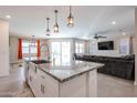 Open-concept kitchen showcases a large island with granite counters, stainless sink, and adjacent living area at 4593 W Bush Bean Way, San Tan Valley, AZ 85144