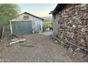 Exterior featuring a stone house, adjacent to a weathered metal shed, capturing a rustic and functional outdoor space at 829 W Spray St, Superior, AZ 85173