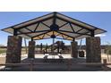 A covered pavilion in a park, featuring stone columns, picnic tables, and playground equipment in the background at 14385 W Sand Hills Rd, Surprise, AZ 85387