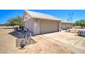 Home exterior showing the tan garage door, electrical wires overhead, and a large dirt lot at 22222 W Lower Buckeye Rd, Buckeye, AZ 85326